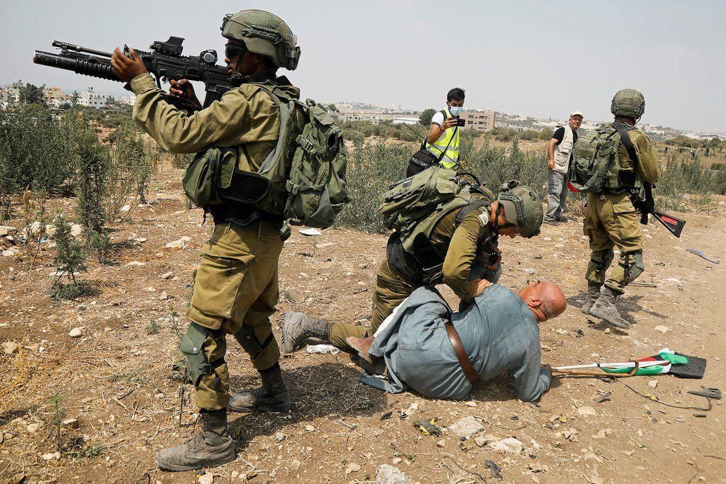 جندي إسرائيلي يجثو على رقبة مسن فلسطيني