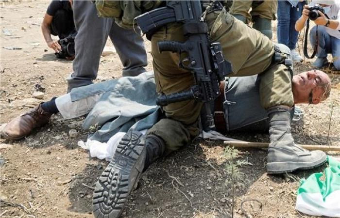جندي إسرائيلي يجثو على رقبة مسن فلسطيني