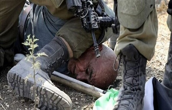 جندي إسرائيلي يجثو على رقبة مسن فلسطيني
